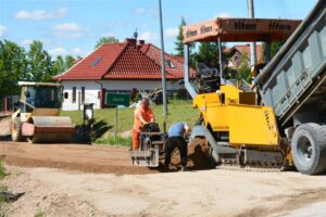 Układanie podbudowy pod drogę Jaśki – Dobki. Na fotografii samochody.