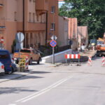 Widok na część ulicy w czasie remontu. Dalej ciągnik i pracownicy.